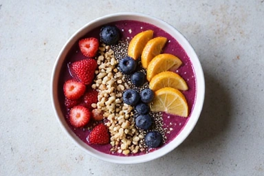 A vibrant smoothie bowl topped with fresh berries, nuts, and seeds, suggesting a healthy breakfast.
